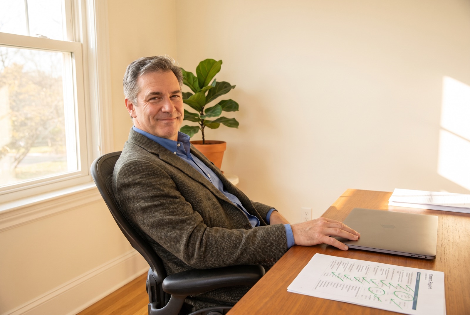 A business owner sitting calmly at a clear desk in morning light with a marked-up report